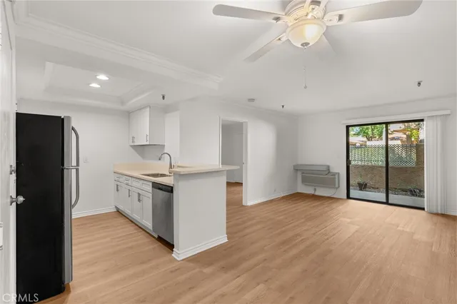 a kitchen with stainless steel appliances kitchen island granite countertop a refrigerator a sink a stove a dining table and chairs with wooden floor