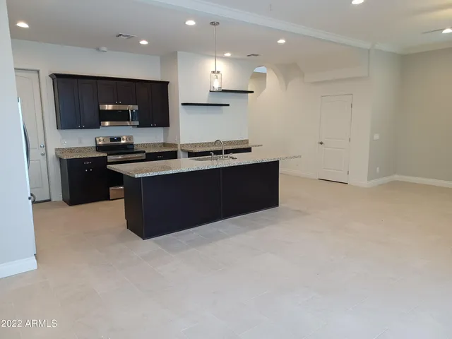 a large kitchen with stainless steel appliances granite countertop a stove top oven a sink dishwasher and a refrigerator with wooden floor