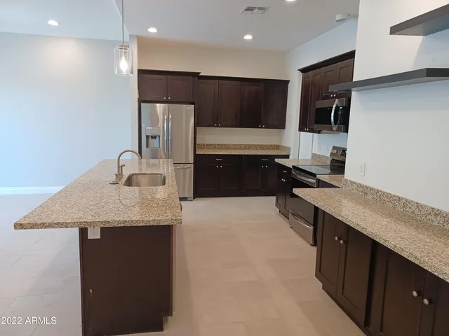 a large kitchen with stainless steel appliances a sink a stove a refrigerator and a oven