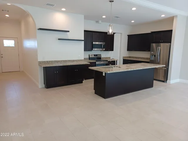 a kitchen with stainless steel appliances kitchen island granite countertop a refrigerator and a stove top oven