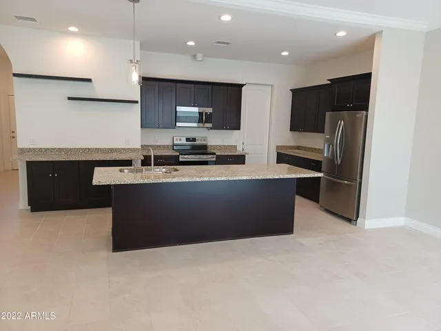 a kitchen with stainless steel appliances a refrigerator a sink a stove a microwave and wooden cabinets