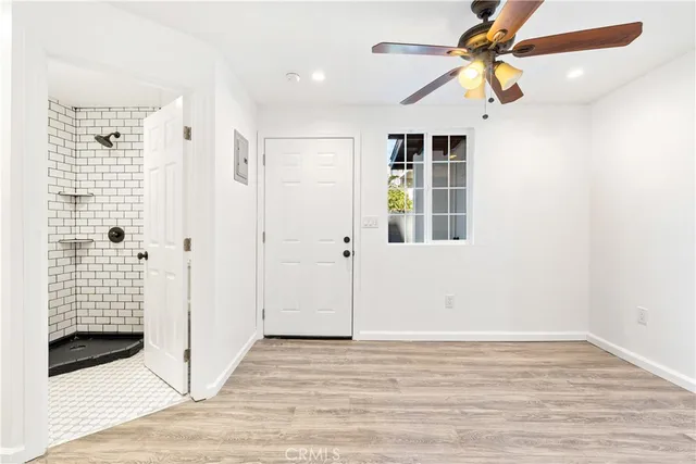 a view of empty room with wooden floor and fan