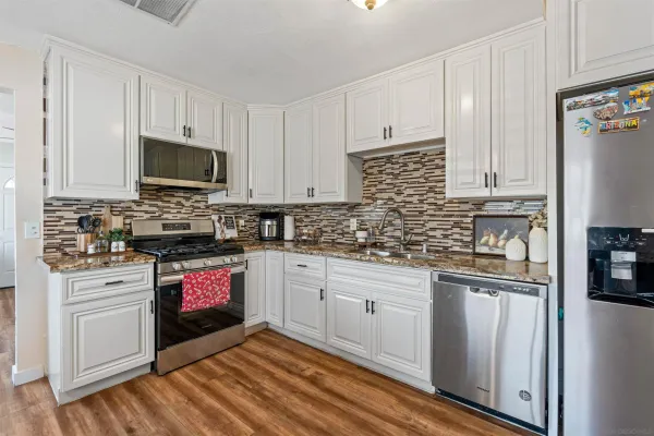 a kitchen with granite countertop a stove top oven sink and cabinets