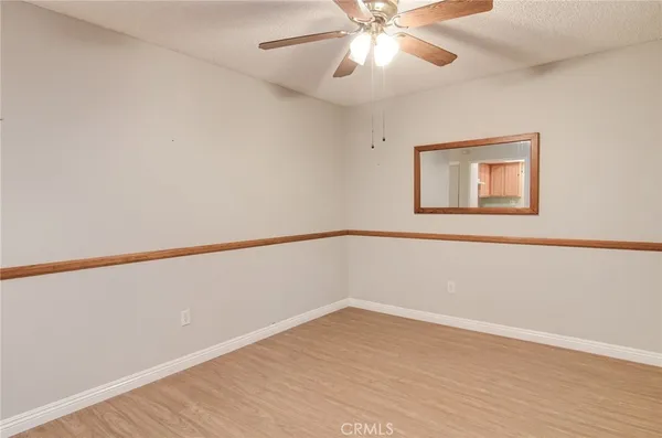 a view of an empty room with wooden floor and a chandelier fan