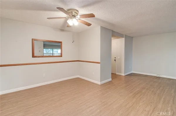 an empty room with wooden floor chandelier fan and windows