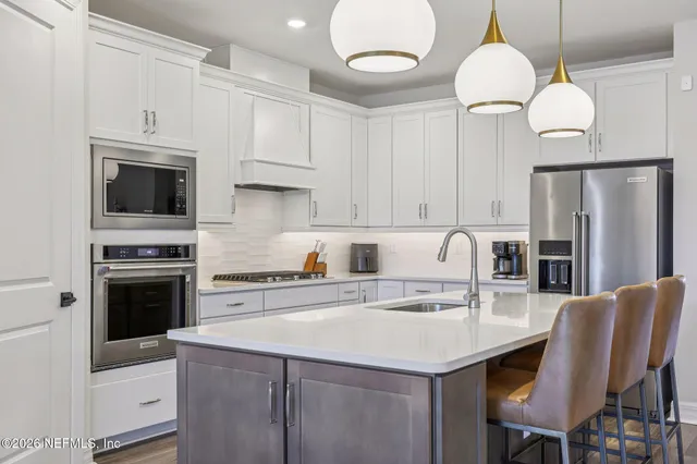 a kitchen with stainless steel appliances kitchen island granite countertop a dining table chairs and white cabinets