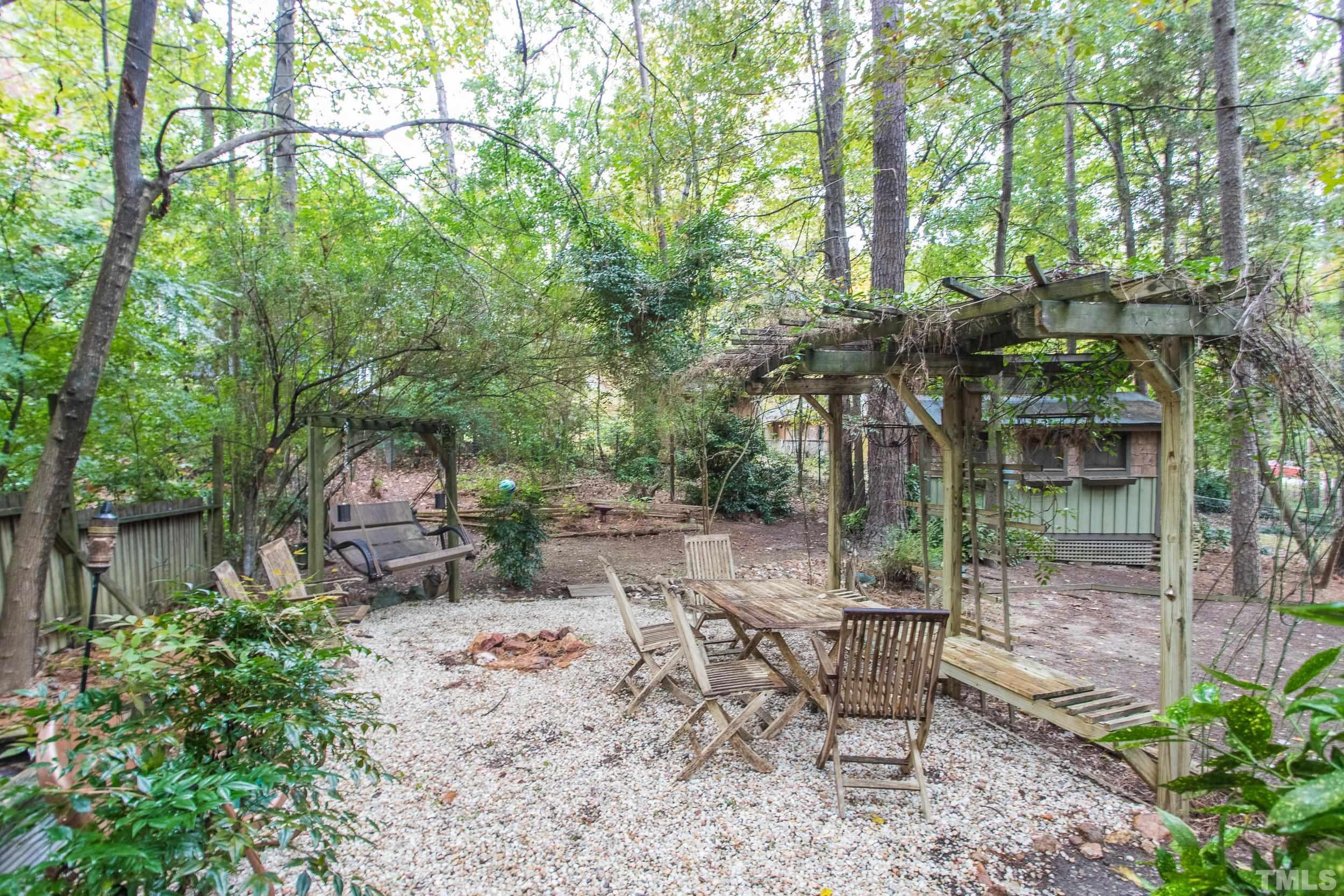 504 Merrie Road Raleigh, NC 27606 - Photo 24 of 25 a backyard of a house with table and chairs large trees