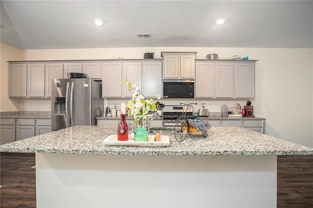 a kitchen with stainless steel appliances a white stove top oven cabinets and a wooden floor