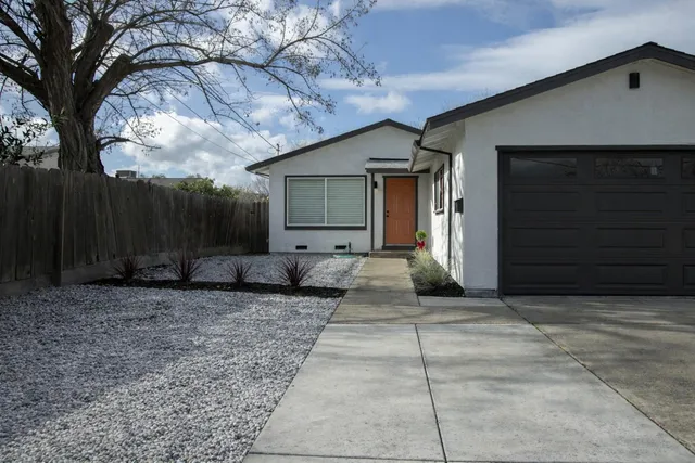a view of a house with a large tree and wooden fence