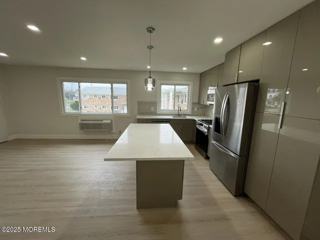 a large kitchen with stainless steel appliances a large counter top a refrigerator and a sink