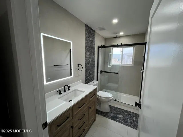 a bathroom with a double vanity sink toilet mirror and shower