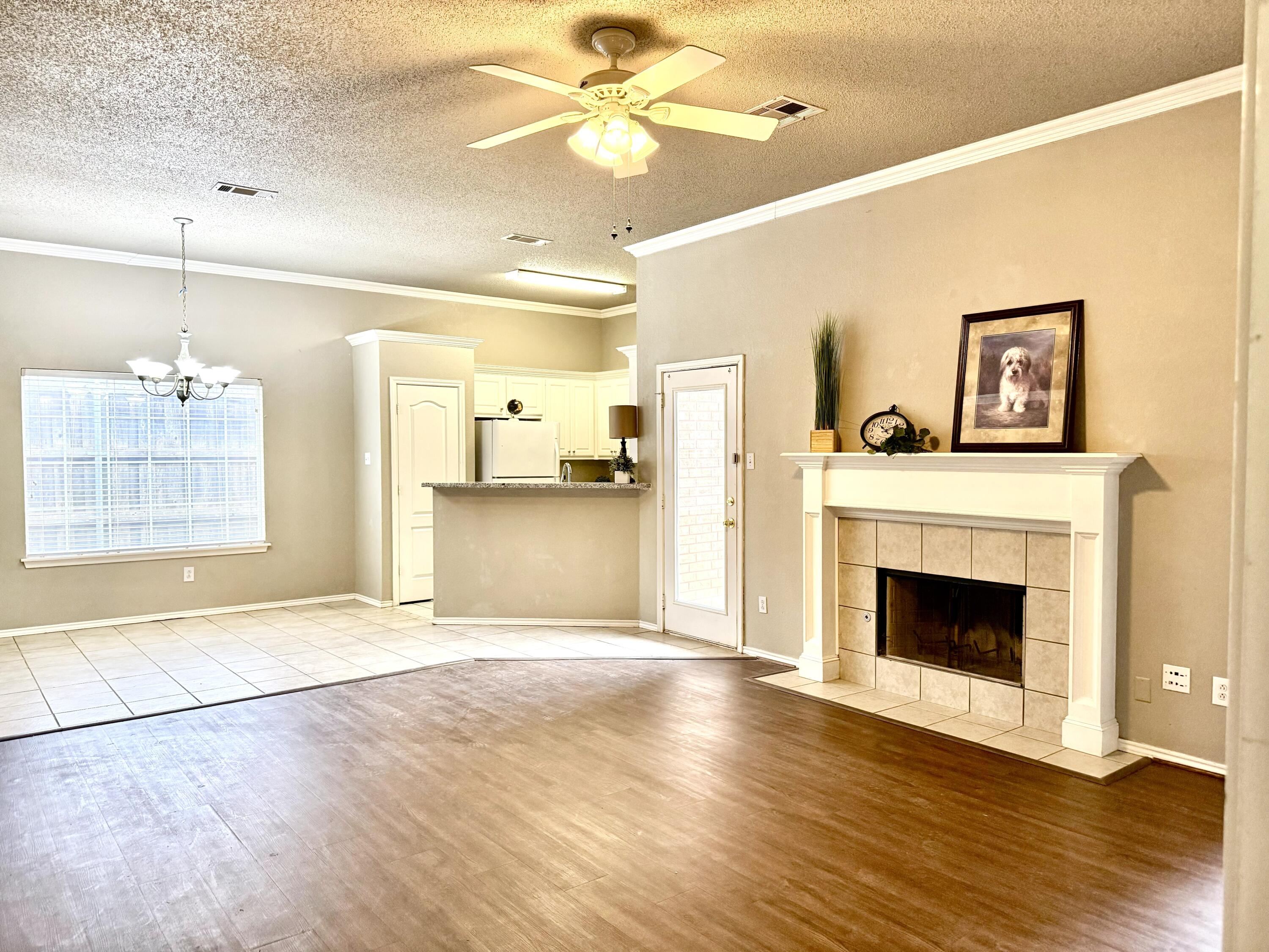 1918 75th Street Lubbock, TX 79423 - Photo 2 of 15 a view of a livingroom with a fireplace a ceiling fan and wooden floor
