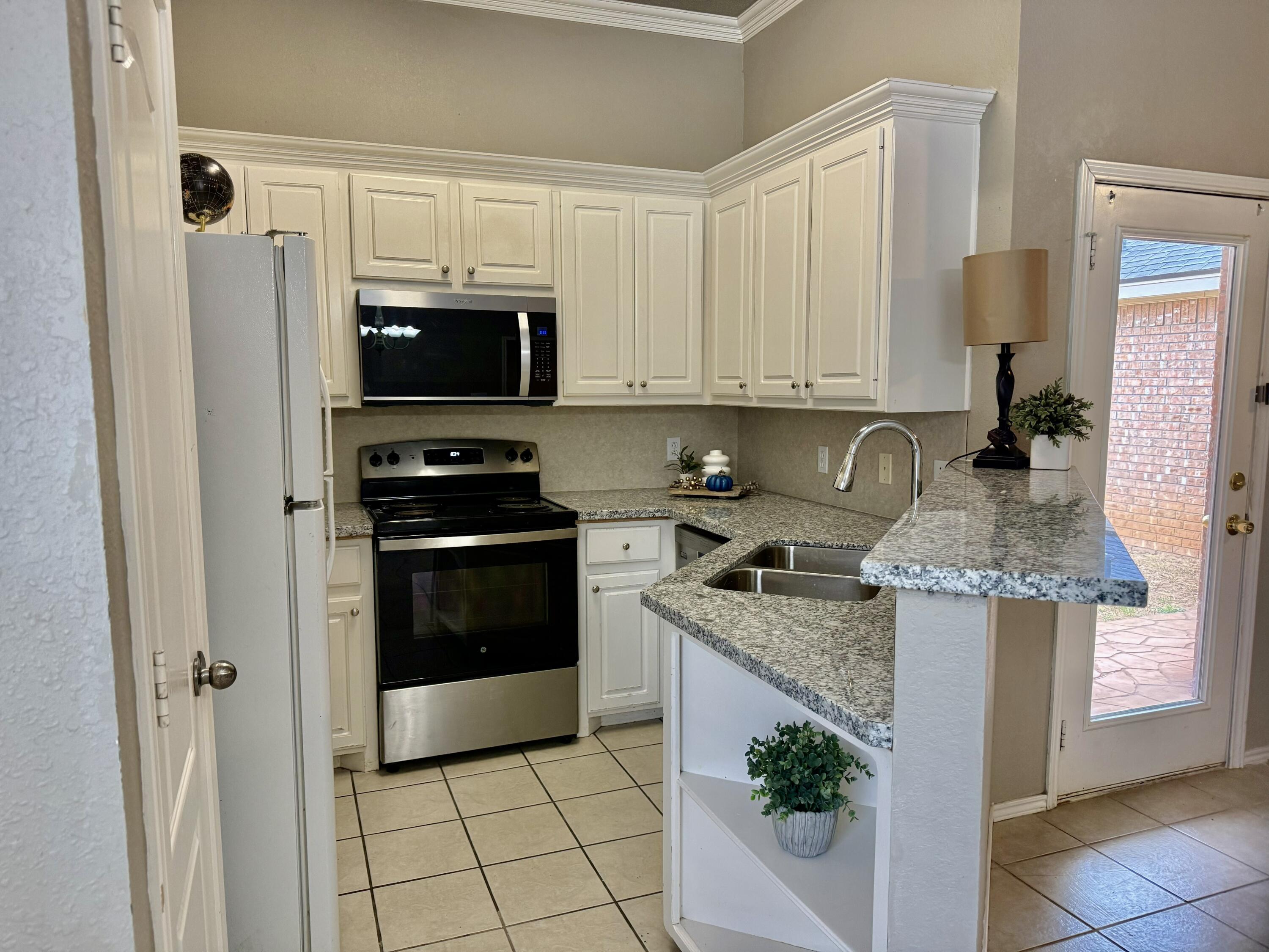 1918 75th Street Lubbock, TX 79423 - Photo 4 of 15 a kitchen with granite countertop a sink stove and refrigerator