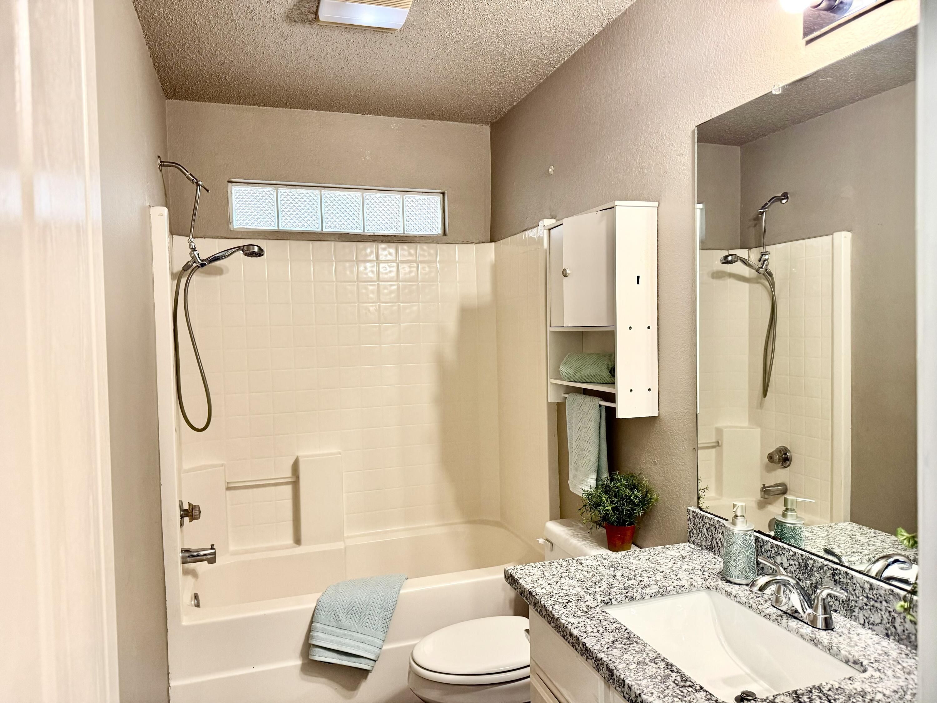 1918 75th Street Lubbock, TX 79423 - Photo 10 of 15 a bathroom with a granite countertop shower sink vanity mirror and toilet