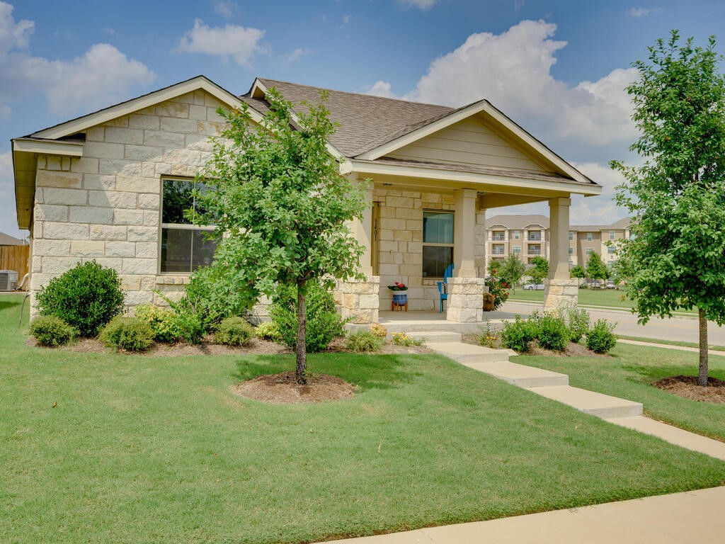 a front view of a house with a yard and potted plants