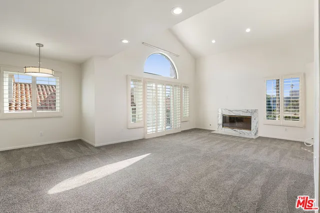 an empty room with windows and fireplace