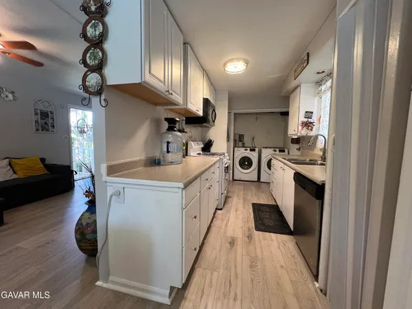 a kitchen with stainless steel appliances a stove top oven a sink a refrigerator white cabinets and wooden floor