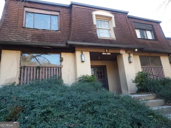a view of a brick house with many windows and a small yard