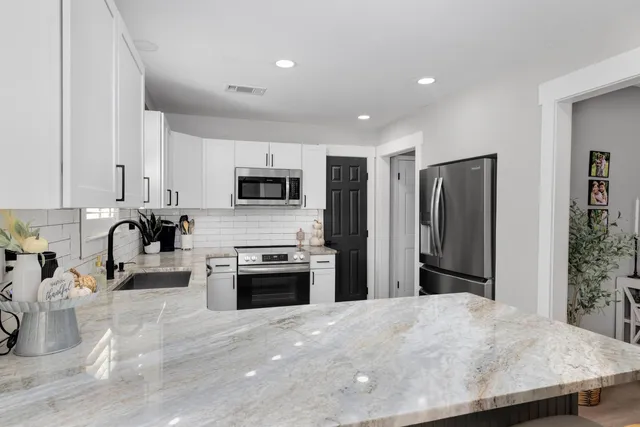 a kitchen with stainless steel appliances granite countertop a refrigerator a stove top oven a sink and dishwasher