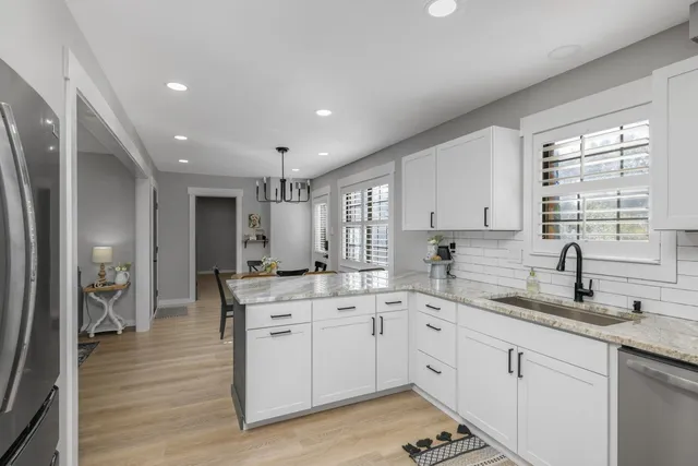 a kitchen with a sink stove cabinets and wooden floor