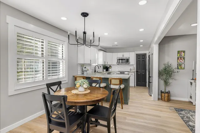 a view of a dining room and livingroom with furniture wooden floor a chandelier