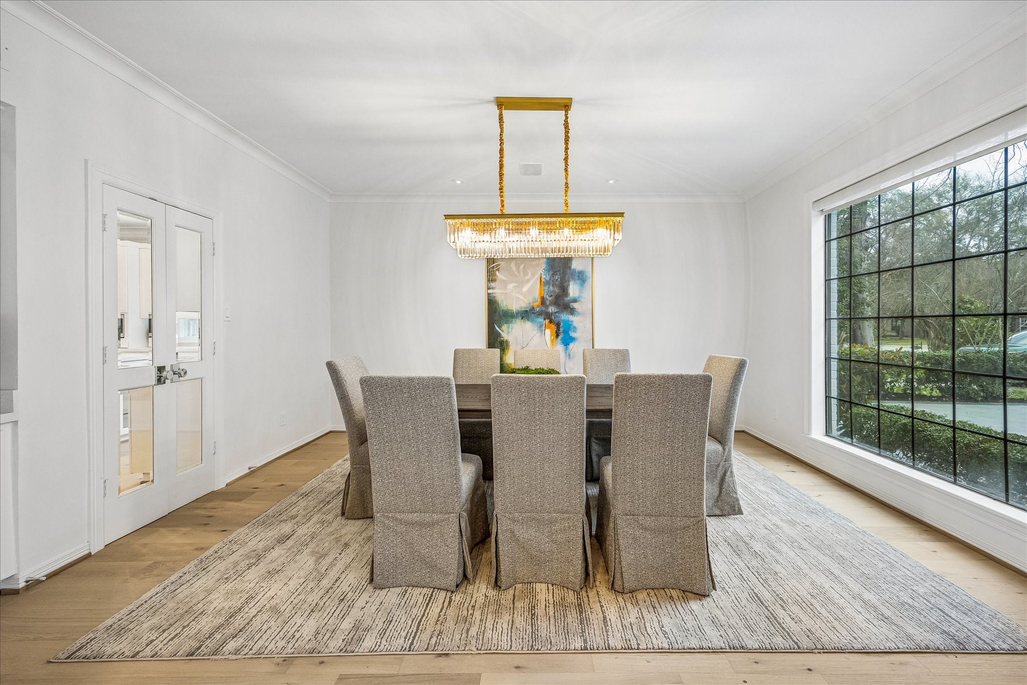 4614 Spruce Street Bellaire, TX 77401 - Photo 11 of 30 a dining room with wooden floor a chandelier a glass table and windows
