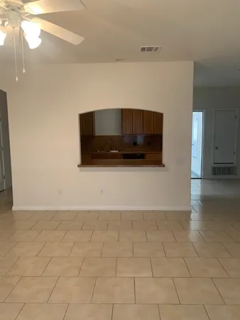 a view of a microwave and an empty room with wooden floor