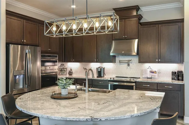 a kitchen with kitchen island granite countertop a sink cabinets and stainless steel appliances