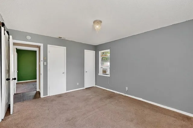 a view of an empty room with window and closet area