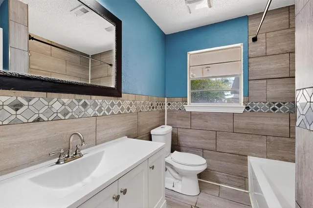 a bathroom with a toilet sink vanity and mirror