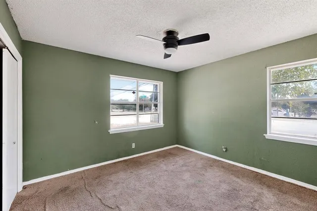 an empty room with a window and a ceiling fan