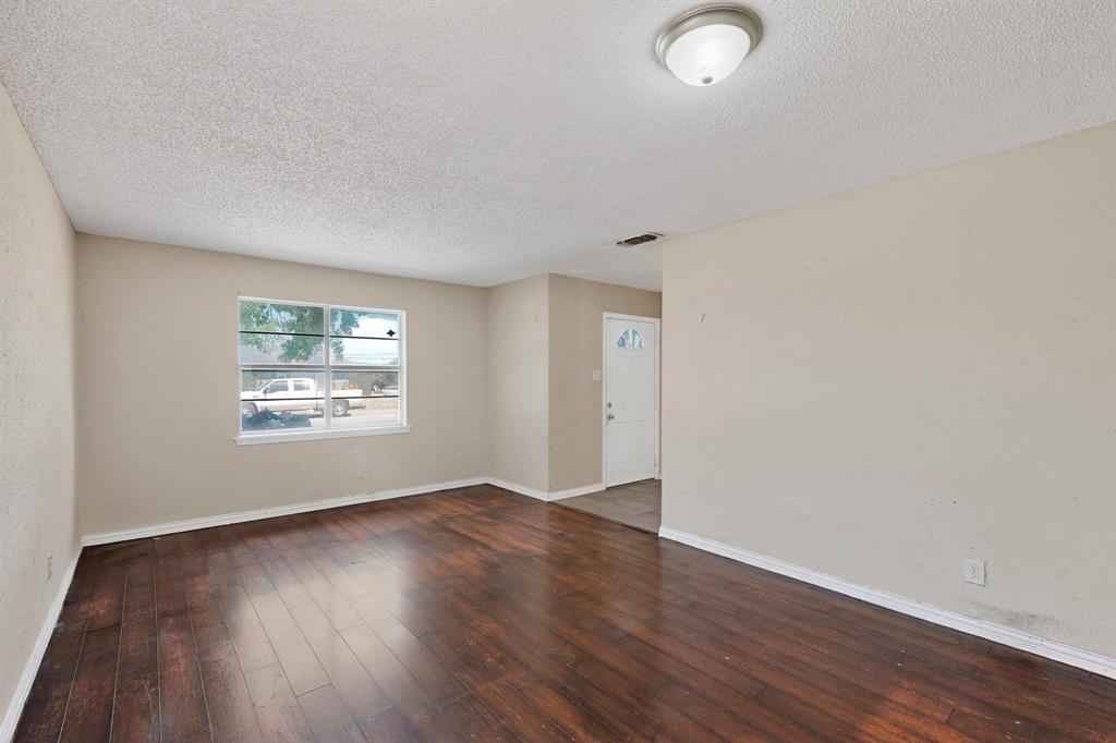 702 Rea Avenue Lancaster, TX 75146 - Photo 6 of 37 an empty room with wooden floor and windows