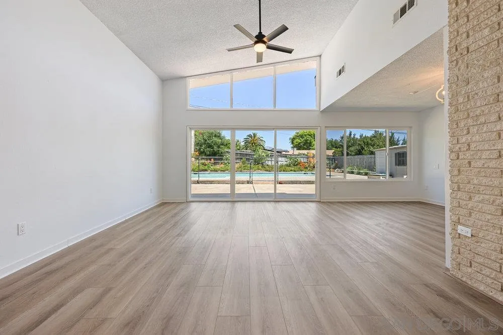 14545 Hillndale Way Poway, CA 92064 - Photo 9 of 27 an empty room with wooden floor fan and windows