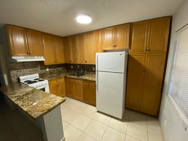 a kitchen with granite countertop cabinets and refrigerator