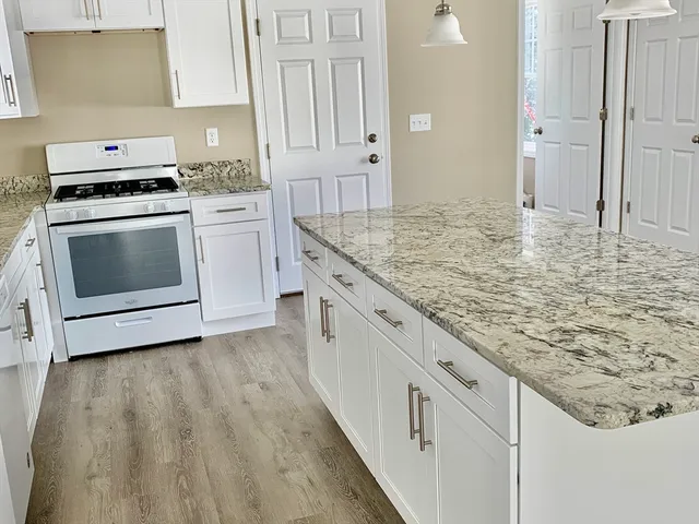a kitchen with granite countertop white cabinets and white appliances