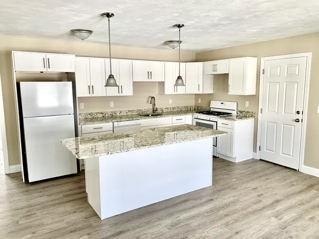 a kitchen with stainless steel appliances granite countertop a sink a stove and a refrigerator