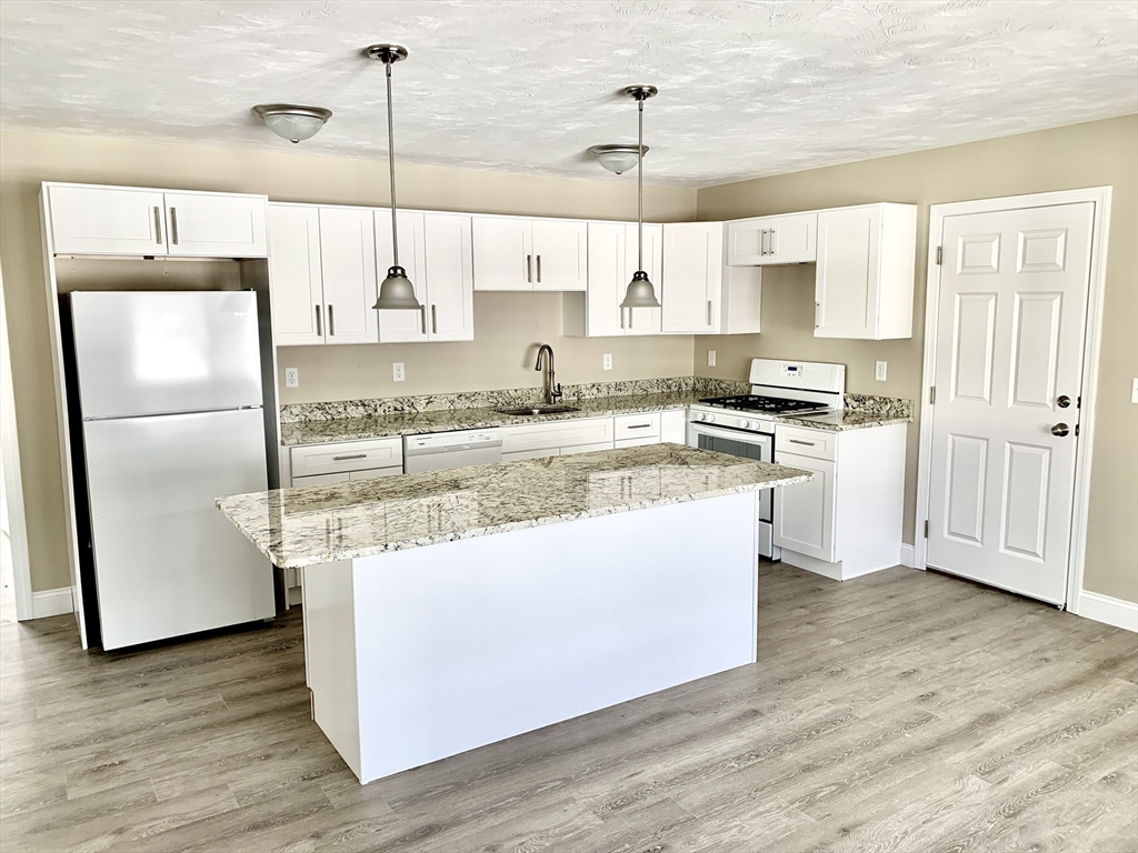 18-22 Burgess Street Lowell, MA 01851 - Photo 8 of 12 a kitchen with stainless steel appliances granite countertop a sink a stove and a refrigerator