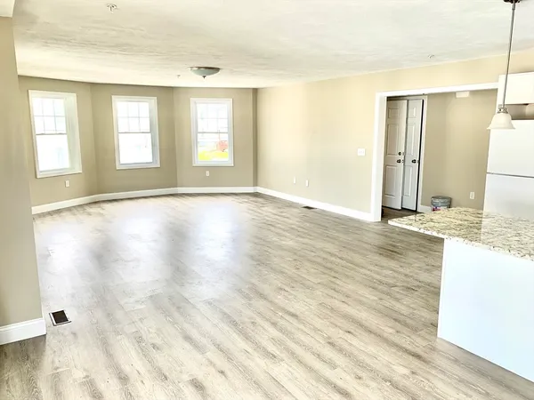 a view of an empty room with window and wooden floor