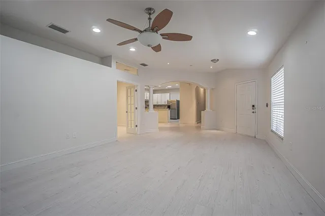 an empty room with a kitchen and a ceiling fan