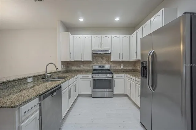 a kitchen with stainless steel appliances granite countertop a sink stove and refrigerator