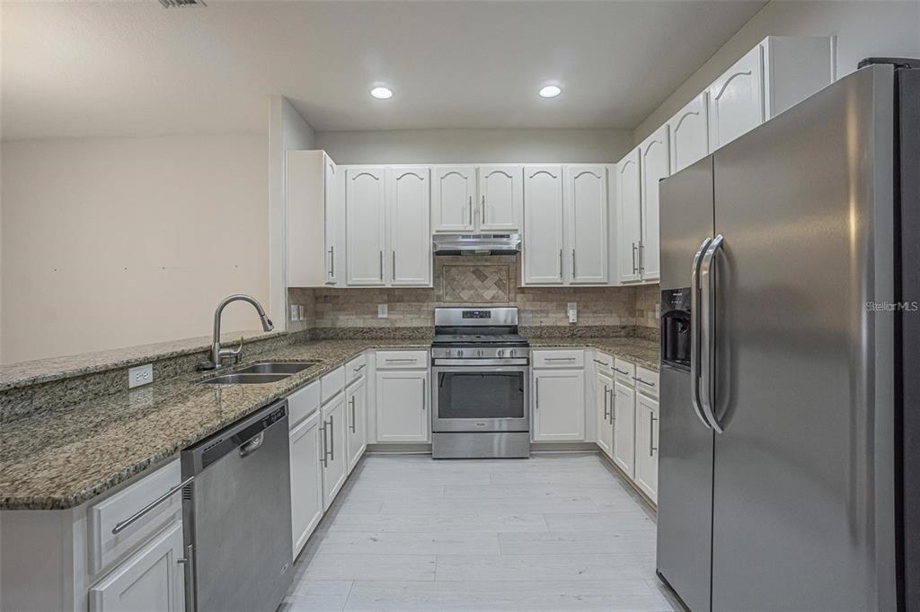 31912 Turkeyhill Drive Wesley Chapel, FL 33543 - Photo 7 of 27 a kitchen with stainless steel appliances granite countertop a sink stove and refrigerator