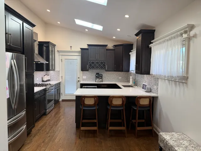 a kitchen with stainless steel appliances granite countertop a sink a stove a refrigerator and island