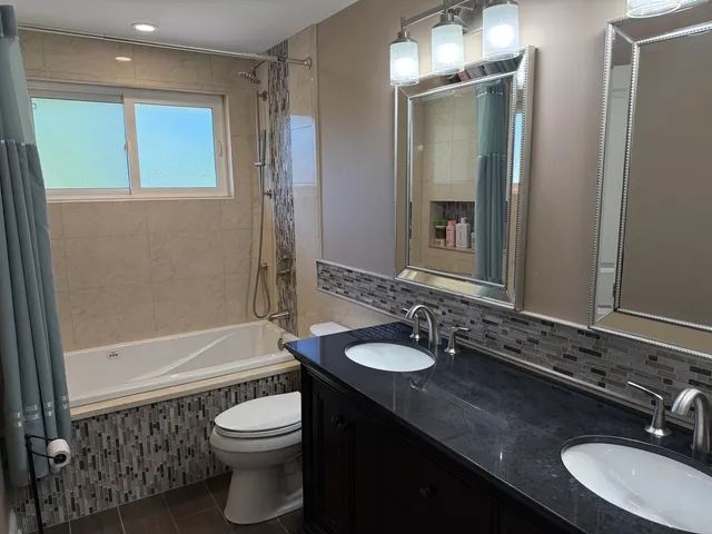 a bathroom with a granite countertop sink toilet a mirror and shower