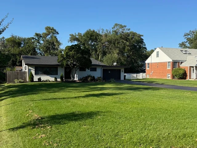 a front view of a house with a yard and trees