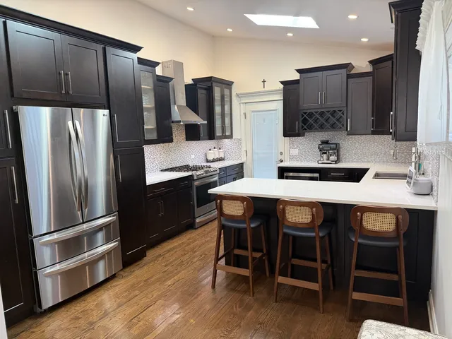 a kitchen with stainless steel appliances a table chairs refrigerator and microwave