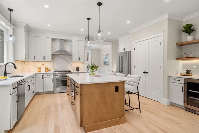 a large kitchen with kitchen island a sink white cabinets and stainless steel appliances