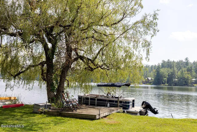 a view of a lake with lawn chairs under an umbrella