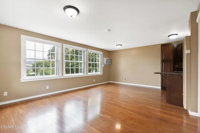 a view of an empty room with wooden floor and a window