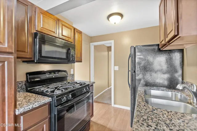 a kitchen with granite countertop a sink stove and refrigerator