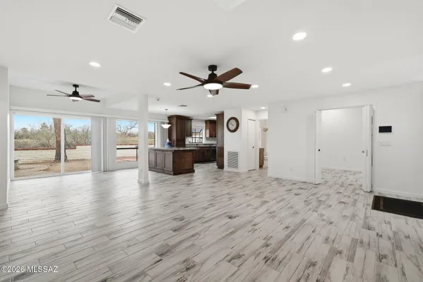an empty room with wooden floor and a ceiling fan